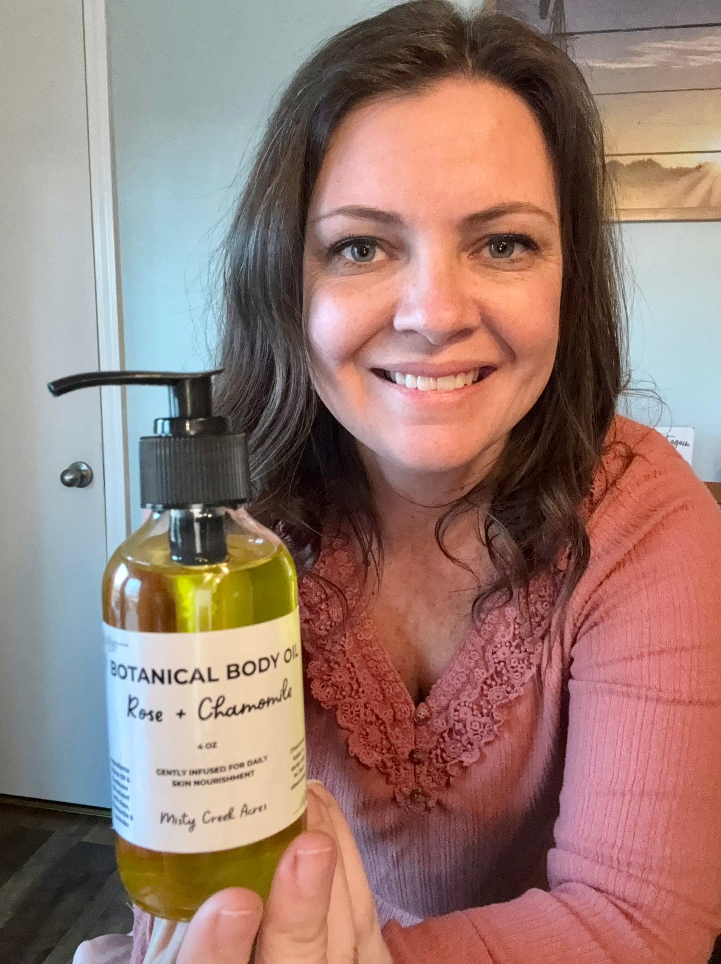 Woman holding a bottle of Botanical Body Oil with a visible label.