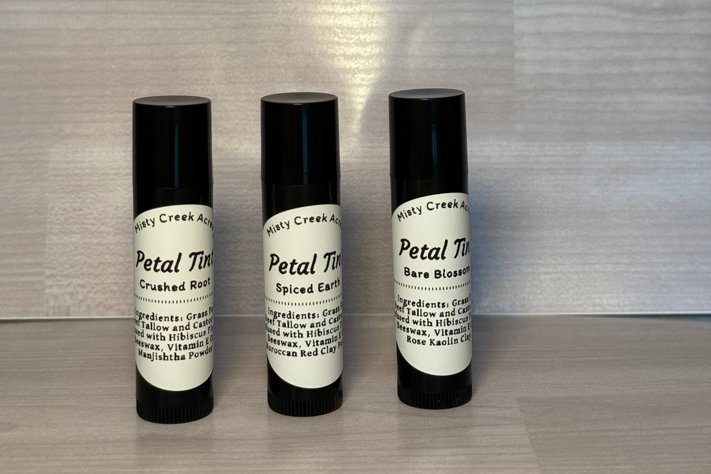 Three black roll-on bottles with white labels on a wooden surface.