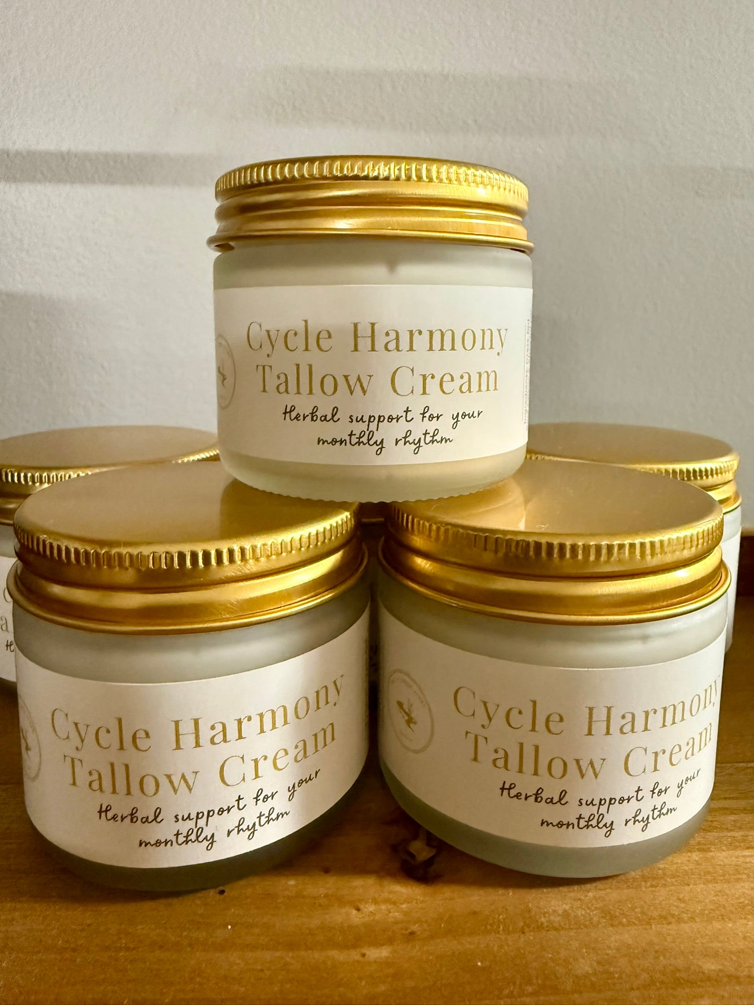 Jars of Cycle Harmony Tallow Cream on a wooden surface with a neutral background