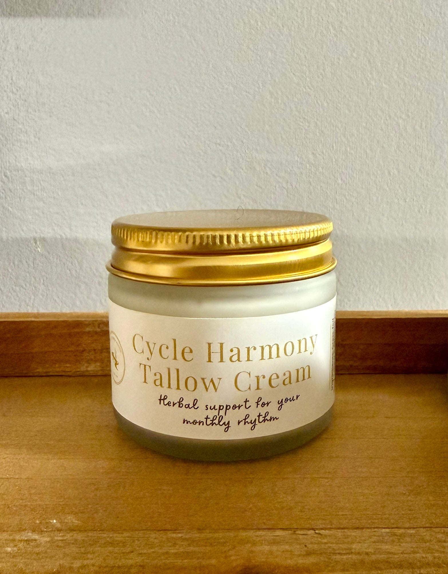 Jar of Cycle Harmony Tallow Cream on a wooden surface with a white background
