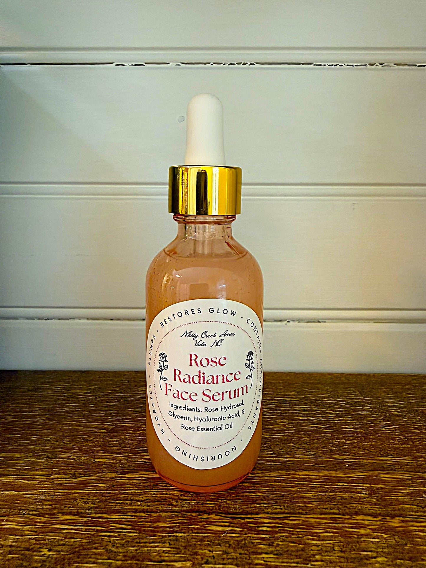 Rose Radiance Face Serum bottle with dropper on a wooden surface