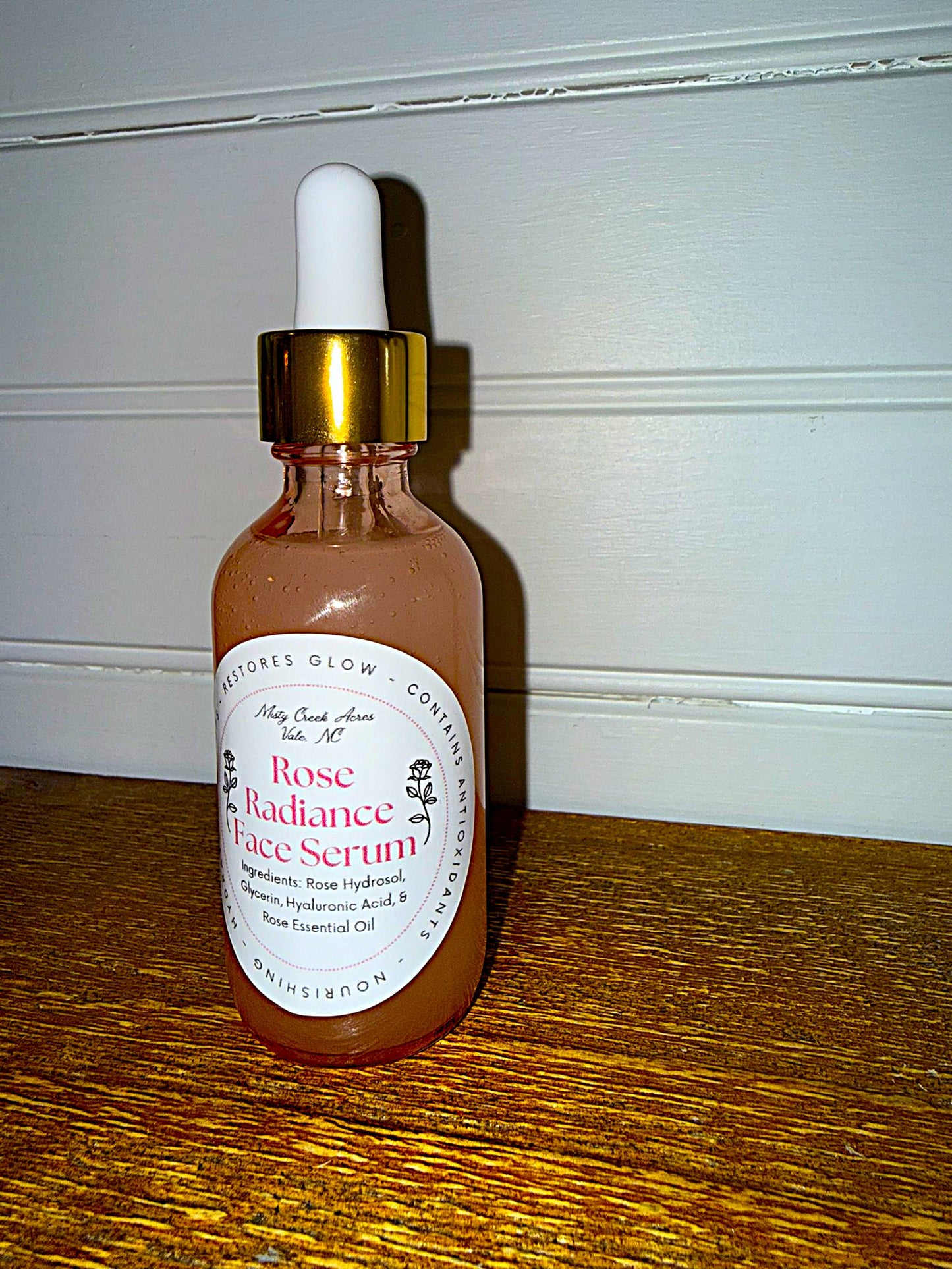 Rose Radiance Face Serum bottle with dropper on a wooden surface