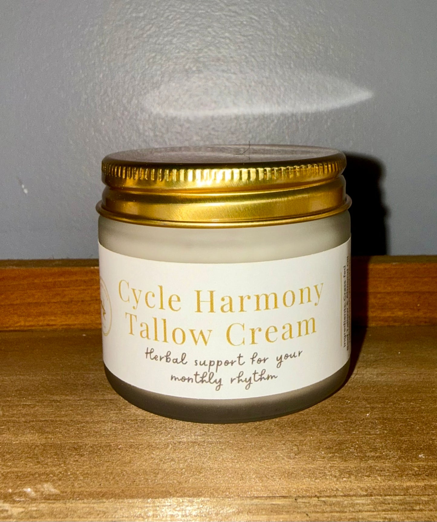 Jar of Cycle Harmony Tallow Cream on a wooden surface with a gray background