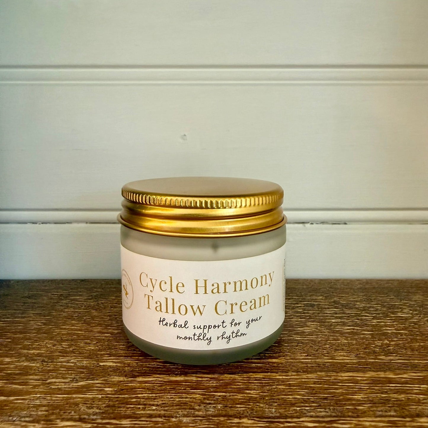 Jar of Cycle Harmony Tallow Cream on a wooden surface with a white wall background