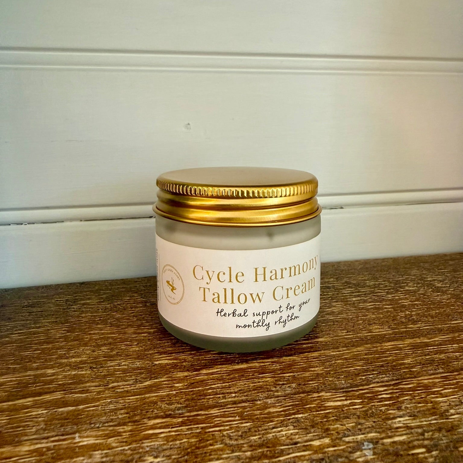 Jar of Cycle Harmony Tallow Cream on a wooden surface with a white background