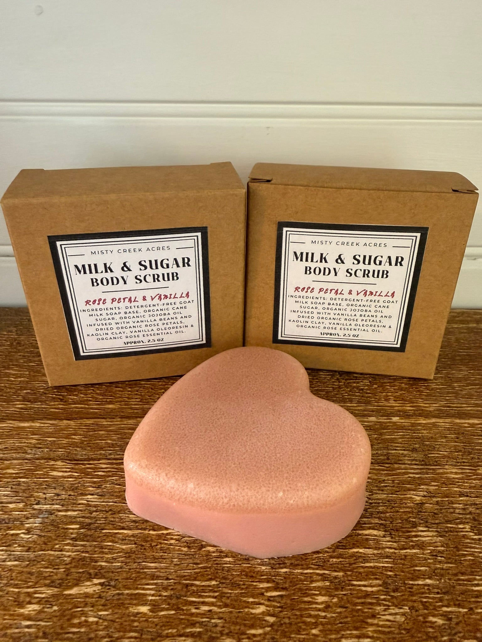 Heart-shaped body scrub with 'Milk & Sugar' packaging on a wooden surface