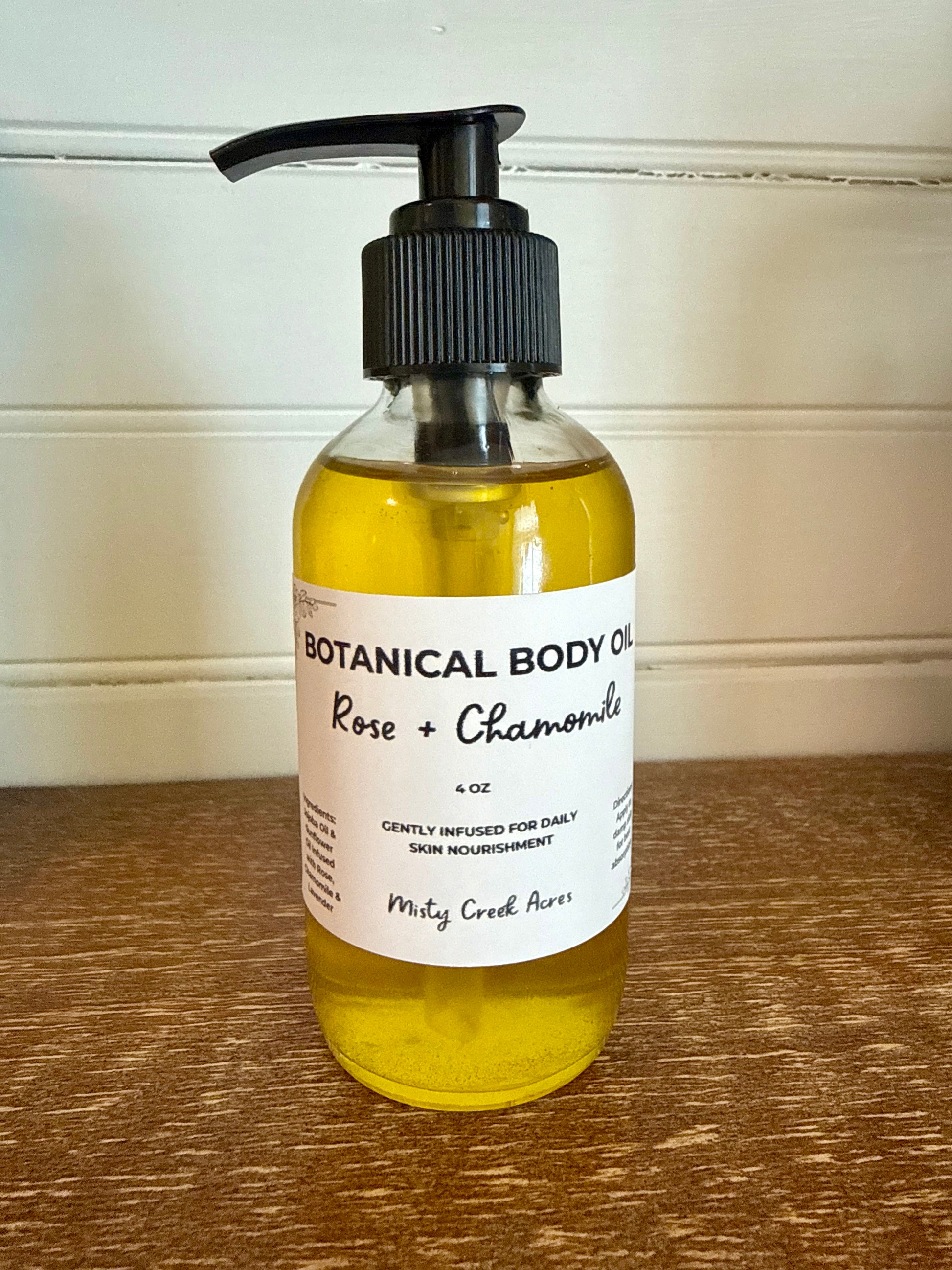 Bottle of botanical body oil with a pump on a wooden surface
